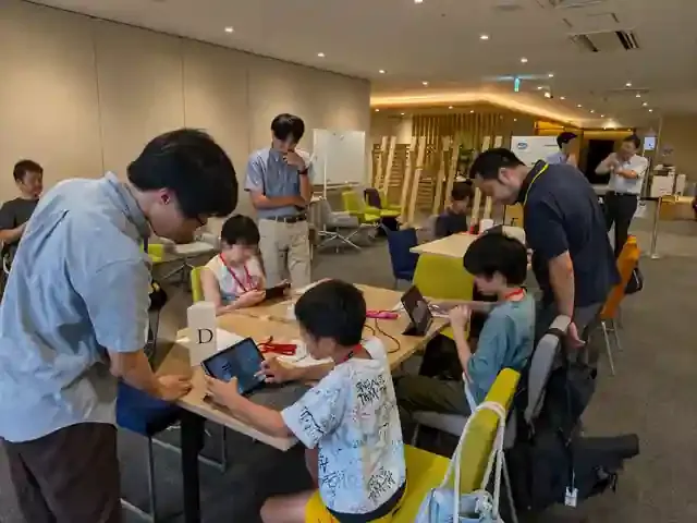 大学生スタッフの支援を受けながら、子どもたちがタブレットやパソコンで防災対策を制作している様子